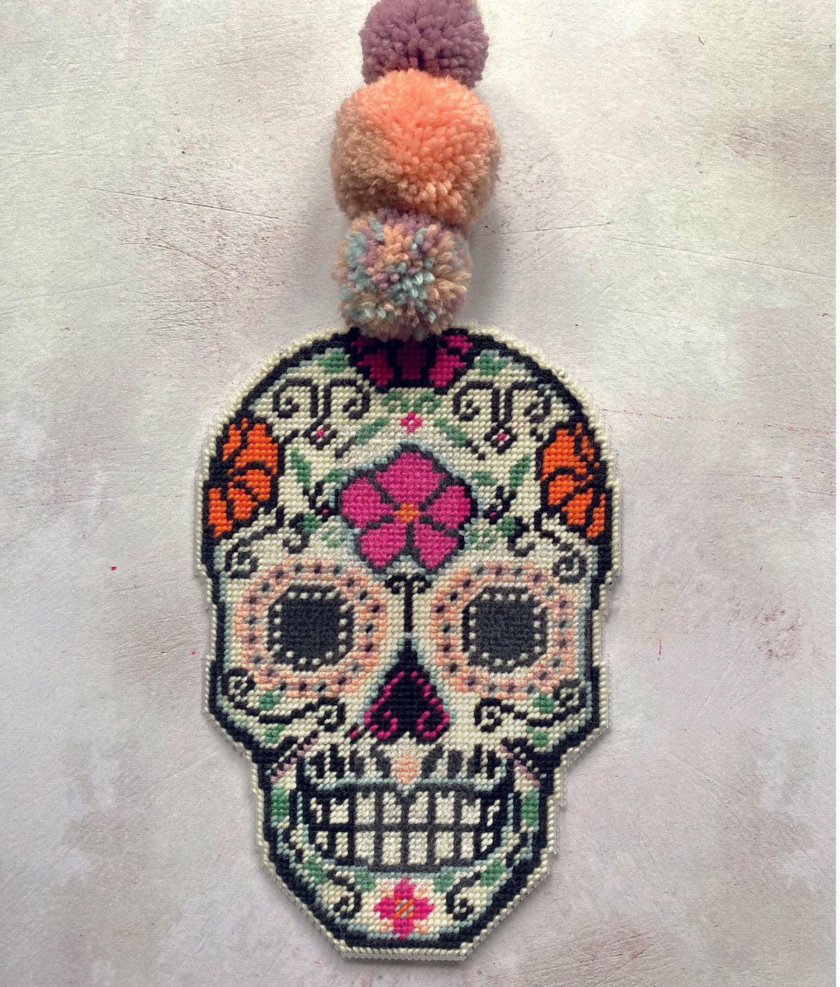 day of the dead needlepoint decoration stitched in vibrant colours of wool in pink and orange