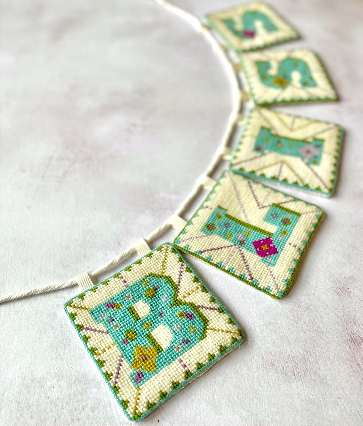 Add a touch of charm to any space with this intricately stitched tapestry bunting decoration. Each tapestry kit includes  vibrant colours of appletons crewel wool and each letter includes exquisite patterns. It effortlessly infuses your surroundings with a bohemian flair. Hang it on walls and mantels to instantly elevate your decor with its unique, handcrafted appeal.