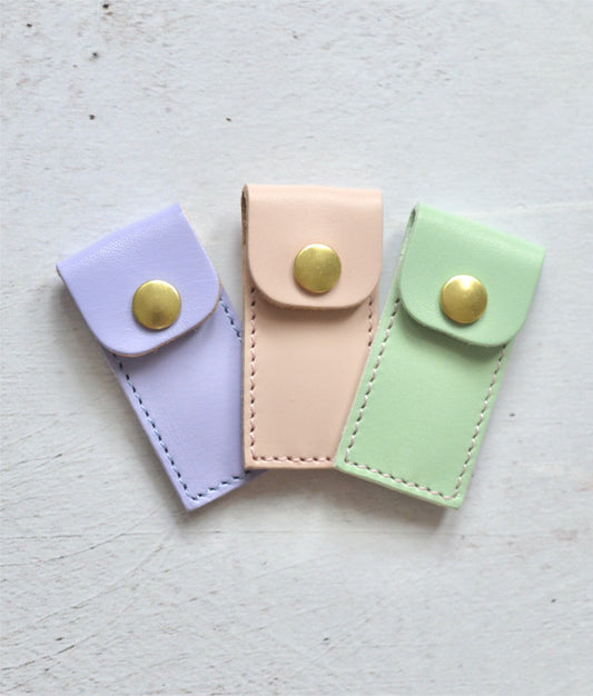pastel coloured leather cases to hold tapestry needles. Colours include lilac, pink and mint green.