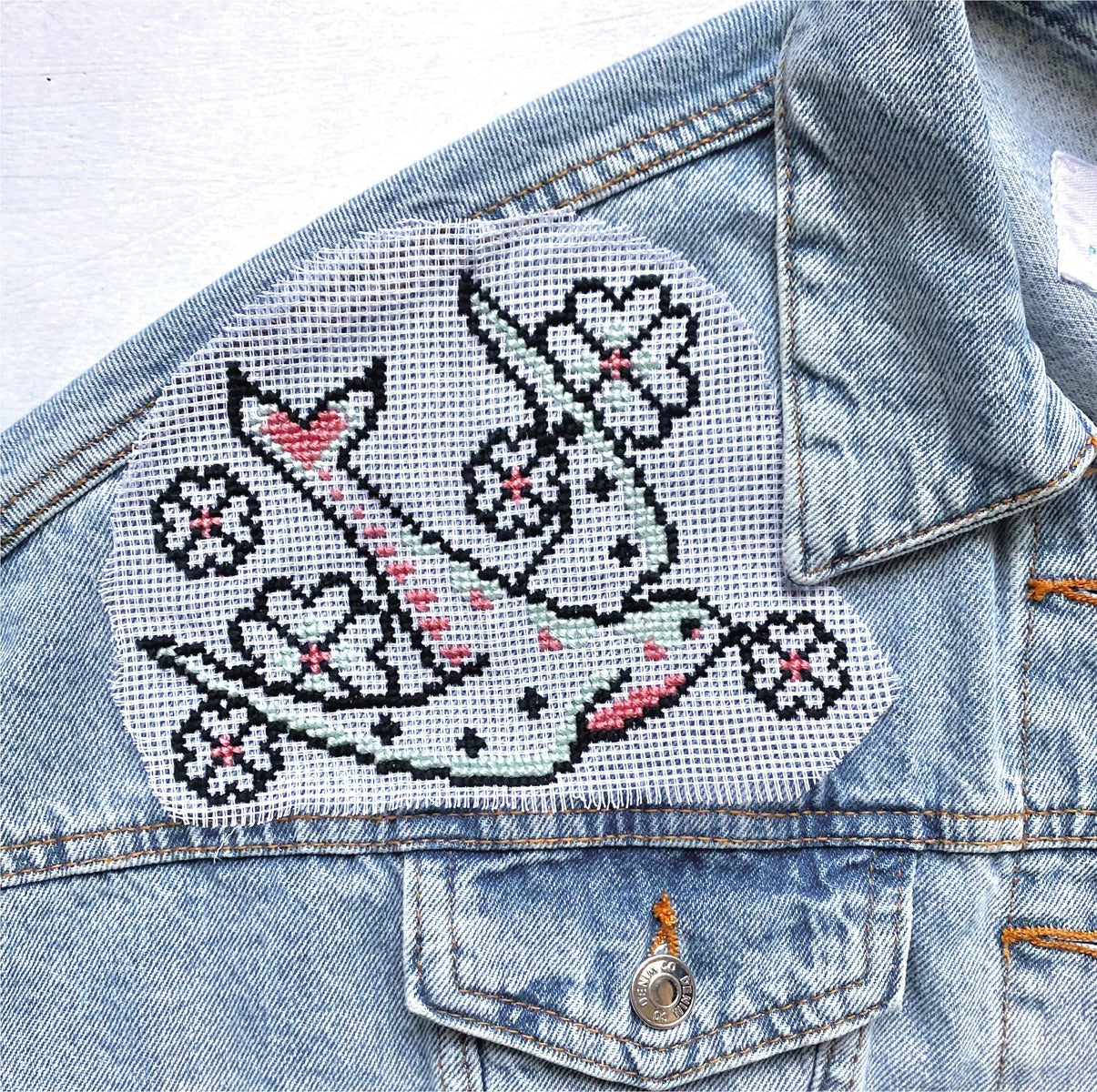 a cross stitch design stitched onto a denim jacket and using waste canvas