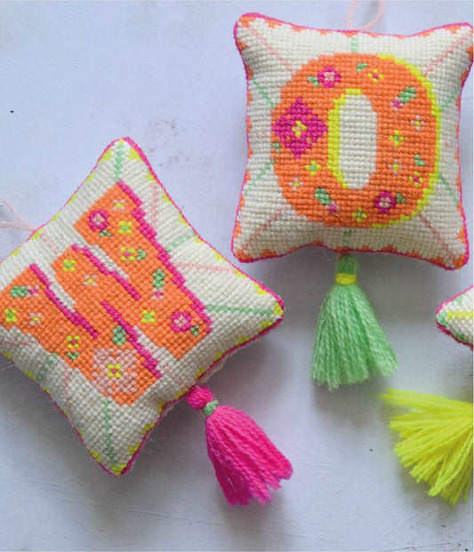 A detailed close up of intricate cross stitching tapestry kit in vibrant neon colours.