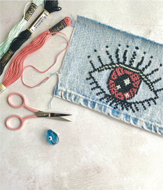 a cross stitch downloadable pattern showing a protective evil eye design using anchor soft cotton threads