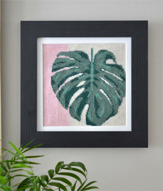 An image of a monstera leaf tapestry kit, showcasing intricate stitching detail and vibrant green hues. The tapestry depicts a single monstera leaf, with its characteristic split patterns and tropical charm, against a plain background. Perfect for nature enthusiasts seeking to bring a touch of botanical beauty into their living space.