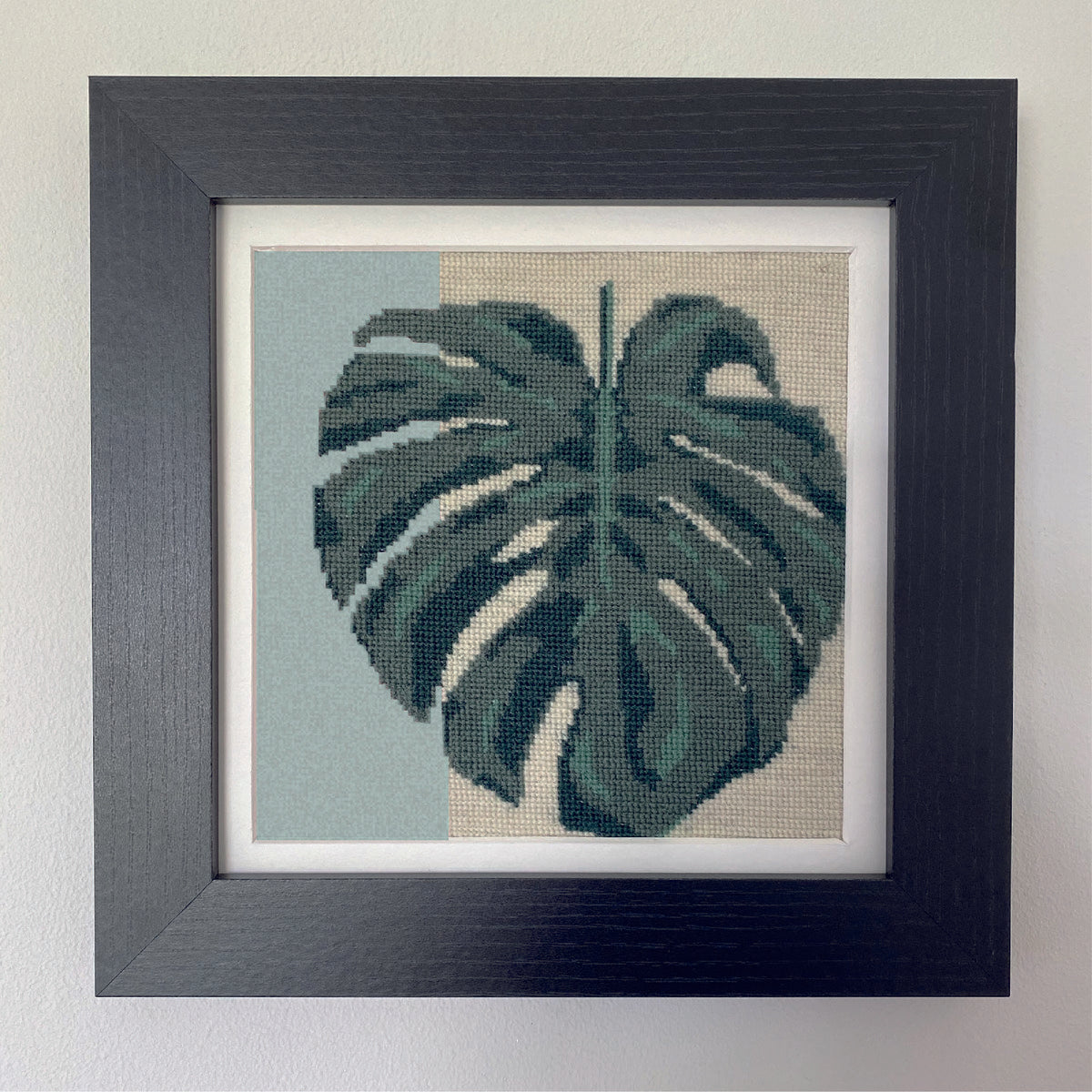 A detailed monstera leaf tapestry kit for adults. Featuring shades of green with a minimal background design.