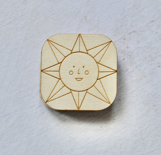 a plywood needle minder with a lazer engraved sunshine face